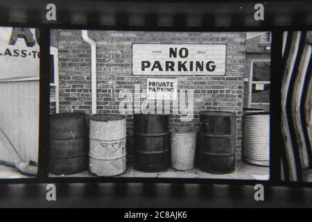 Fin 70s vintage contact imprimé noir et blanc photographie d'un tas de poubelles devant un panneau no parking. Banque D'Images