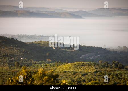 Le brouillard enveloppe une vallée sous les collines ondulantes et les communautés du district de Lyantonde, en Ouganda, en Afrique de l'est. Banque D'Images