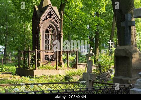 Saint-Pétersbourg, Russie - 22 juin 2020 : une tombe ornée au milieu d'une végétation luxuriante au cimetière luthérien de Smolenskoye. Banque D'Images