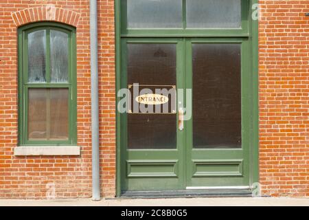 Panneau d'entrée générique sur la fenêtre de porte verte dans un mur extérieur en brique orange. Banque D'Images