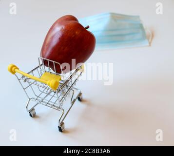 Chariot jaune miniature avec pomme pleine taille avec masque de protection bleu à l'avant sur fond blanc Banque D'Images