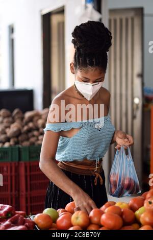 Jeune femme latine noire achetant des légumes dans le masque facial Banque D'Images