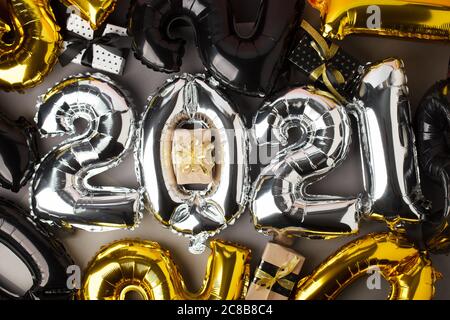 Bonne célébration du nouvel an 2021. Ballons or noir et argent en aluminium chiffre 2021 sur fond gris. Pose d'appartement, décoration saisonnière de fête de Noël, Ban Banque D'Images