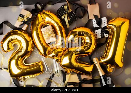 Ballons de film sous forme de nombres 2021. Nouvel an, joyeux noël. Ballons d'air doré, boîte cadeau, champagne et verres à vin. Hol Banque D'Images