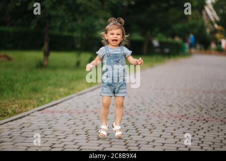 Petite fille mignonne dix-huit mois de marche dans le parc et de sauter Banque D'Images