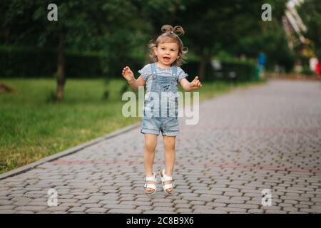 Petite fille mignonne dix-huit mois de marche dans le parc et de sauter Banque D'Images