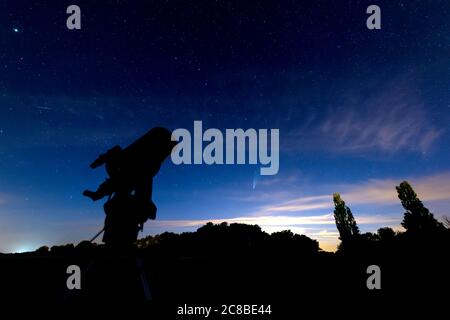 Silhouette de télescope sous un ciel étoilé bleu foncé au crépuscule, comète neowise visible sous la constellation du Grand Ours (Ursa Major). Banque D'Images