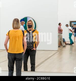 Angela Berg se tient devant le grand objet miroir sans cadre, peut-être l'œuvre « Spiegel » (Mirror, 2014) de Gerhard Richter, dans l'exposition de collection « Silent Vision – Images of Calm and Quiet » à la Fondation Beyeler à Riehen, Suisse. Le miroir reflète un visiteur devant la toile ronde colorée de la salle voisine, ainsi que plusieurs visiteurs en conversation à l'arrière-plan ; l'exposition, organisée par Raphaël Bouvier, s'est tenue en 2020 jusqu'au 15 novembre. Banque D'Images
