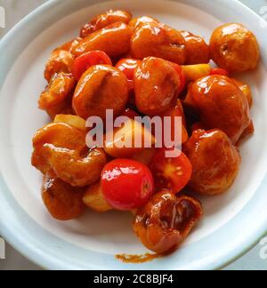 La cuisine traditionnelle chinoise, le porc doux et notre avec tomate et pomme de pin dans la plaque blanche Banque D'Images