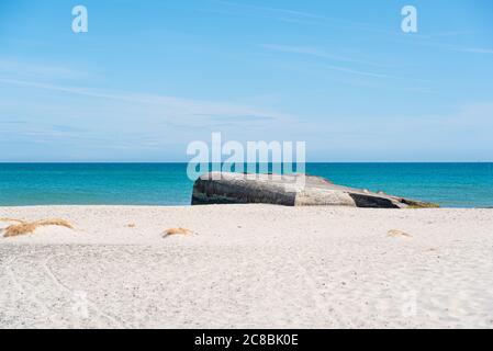 Un vieux bunker en béton s'est enfoncé dans le sable sur une plage. Banque D'Images