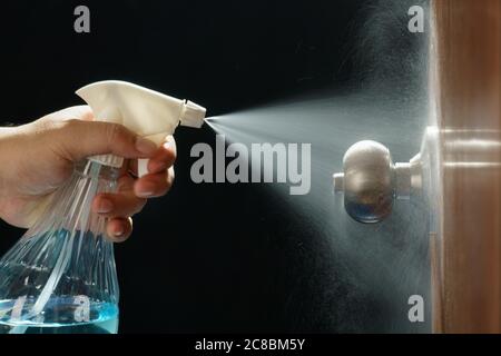 Nettoyage du bouton de porte avec un aérosol d'alcool pour la prévention du Covid-19 (coronavirus). Banque D'Images