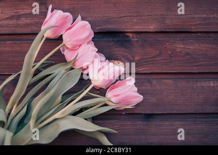 Bouquet de tulipes roses sur fond de bois brun. Vue de dessus, espace de copie. Rangée de tulipes sur fond en bois avec espace pour message. Fête des mères Banque D'Images