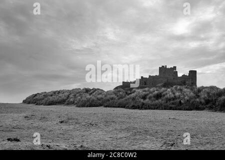 Château de Bamburgh, Northumberland, Angleterre, Royaume-Uni, de l'autre côté du sable de Bamburgh Beach. Version noir et blanc Banque D'Images