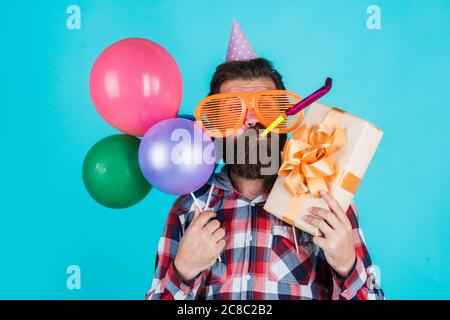 Votre commande est prête. Brutal homme en fête. Drôle d'homme dans un chapeau d'anniversaire. Joyeux Noël. Fête de la fête, fête, fête, fête, fête, fête, ballons, fête, anniversaire, gestionnaire d'événements avec boîte cadeau. Banque D'Images