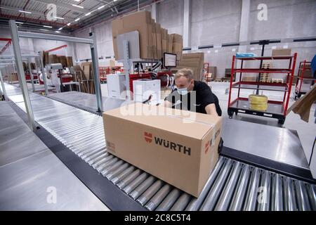 23 juillet 2020, Baden-Wuerttemberg, Kupferzell: Un employé du Groupe Würth place un carton sur un tapis roulant dans un entrepôt de manutention. Le groupe Würth concentre ses entrepôts logistiques externes à Kupferzell, non loin de son siège. Photo: Marijan Murat/dpa Banque D'Images