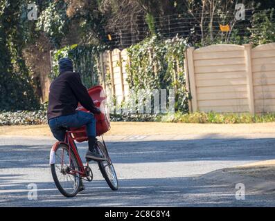 Alberton, Afrique du Sud - un postier non identifié livre le courrier à vélo aux maisons dans une image de quartier résidentiel en format horizontal Banque D'Images