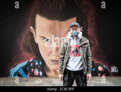 Portrait de l'artiste de rue Akse P19, debout devant ses peintures murales Banque D'Images