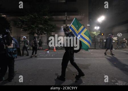 Portland, États-Unis. 23 juillet 2020. Un manifestant porte un drapeau de Portland devant le palais de justice fédéral de Portland, en Oregon, le 23 juillet 2020. (Photo par Alex Milan Tracy/Sipa USA) crédit: SIPA USA/Alay Live News Banque D'Images