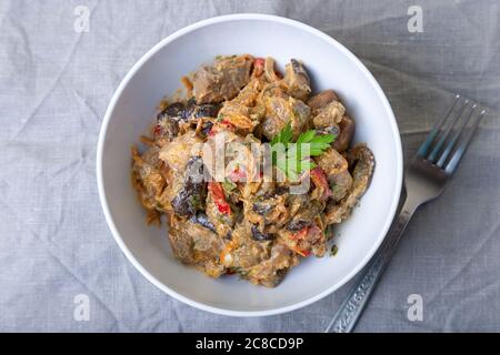 Porc avec aubergines, tomates, poivrons et carottes dans une sauce crémeuse. Gros plan. Banque D'Images