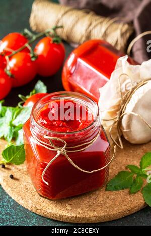 Pâte de tomate. Sauce tomate fraîche et savoureuse avec tomates mûres et basilic sur fond de pierre ou d'ardoise. Banque D'Images