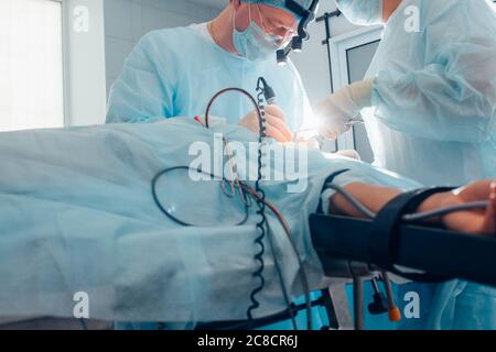 Plan horizontal d'une patiente couchée sur la table d'opération de l'équipe de chirurgiens de la salle de chirurgie travaillant à l'hôpital People Vitality Medicine Banque D'Images