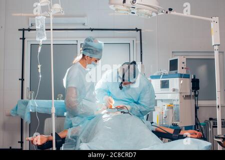 Chirurgien effectuant une chirurgie esthétique du nez dans la salle d'opération de l'hôpital. Chirurgien dans le masque portant des loupes chirurgicales pendant l'intervention médicale. Nez augmenter Banque D'Images