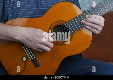 Un homme à la maison avec des mains nerveuses joue une musique classique de jazz de guitare. Banque D'Images