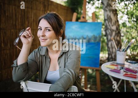 Un artiste heureux tenant des lunettes dans un studio d'art Banque D'Images