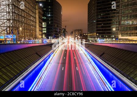 Des sentiers légers sur une route à travers le quartier européen à Bruxelles, en Belgique, la nuit. Exposition longue. Banque D'Images