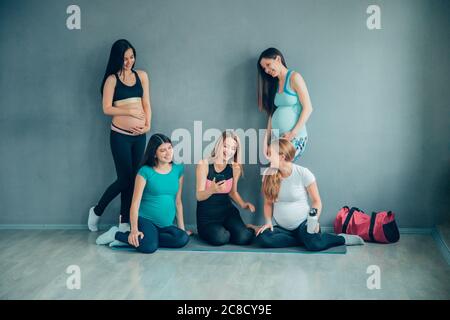 grossesse, sport, fitness, personnes et mode de vie sain concept - groupe de femmes enceintes heureux parlant en salle de gym Banque D'Images