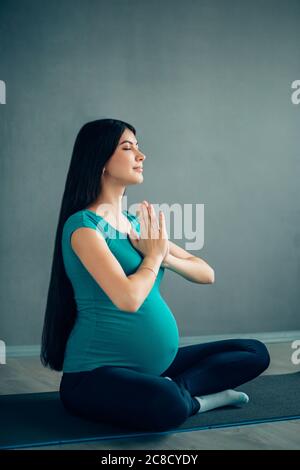 Grossesse yoga. Jeune femme enceinte faisant du yoga à la maison. Banque D'Images