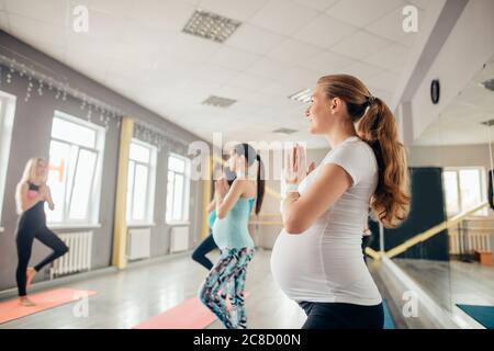 Heureux les femmes enceintes en cours de standing en posture de l'arbre dans un studio de remise en forme Banque D'Images