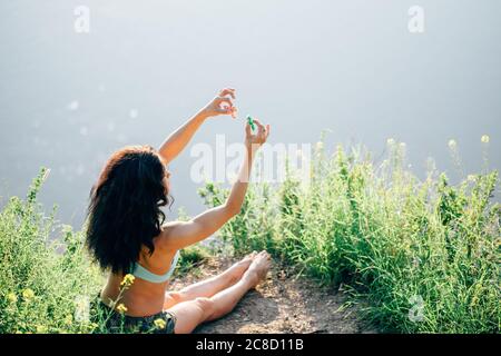 femme assise près de la rivière et jouant avec un spinner de violon Banque D'Images