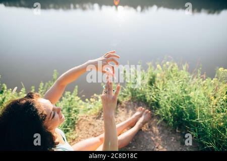 femme assise près de la rivière et jouant avec un spinner de violon Banque D'Images