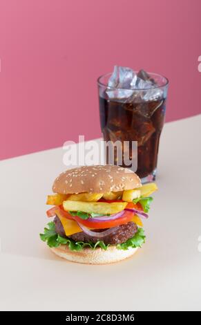 Hamburger de bœuf frais et juteux avec frites placées sur du rose arrière-plan créatif et tendance Banque D'Images