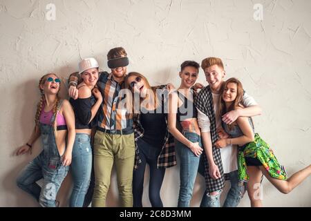 Groupe de jeunes belles femmes et hommes amis se penchent contre un mur intérieur ayant le plaisir - réseau social, concept d'amitié Banque D'Images