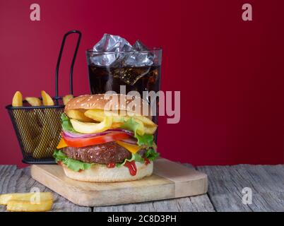 Hamburger de bœuf frais et juteux avec frites et cola placé sur un fond en bois avec espace de copie Banque D'Images