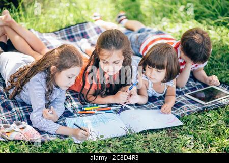 Groupe de enfants peint à l'easel dans le parc Banque D'Images