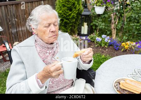 Une vieille femme en fauteuil roulant buvant du thé sur la terrasse. Photo de haute qualité Banque D'Images