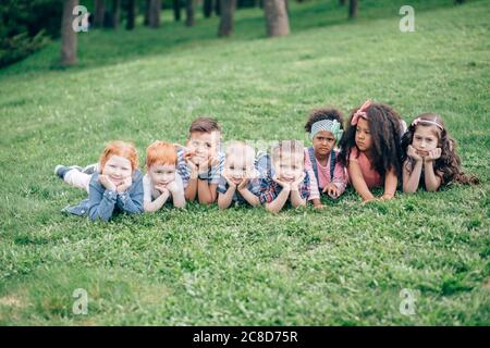 Les enfants souriants s'amusent à l'herbe. Enfants jouant à l'extérieur en été. Les adolescents communiquent à l'extérieur Banque D'Images