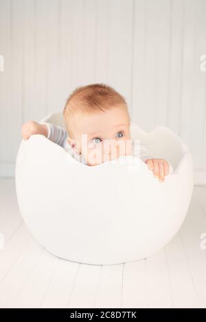 Beau petit bébé à l'intérieur d'un œuf blanc Banque D'Images