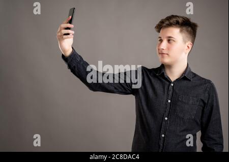 Portrait d'un homme sérieux et élégant habillé avec une chemise noire décontractée prenant photo selfie isolé sur fond gris avec espace de copie advertisi Banque D'Images