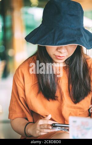 Fille asiatique assis dans un café jouant téléphone mobile pour les médias sociaux pendant les vacances, fille se détendant dans un café pour les vacances, portrait de fille mignonne Banque D'Images