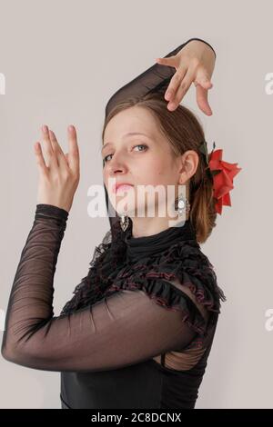 Belle jeune femme dansant le flamenco dans une robe noire. Portrait vertical sur fond blanc. Banque D'Images
