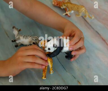 les mains des enfants comme elle joue avec des figurines d'animaux sur un banc. Elle place, se déplace et fait la voix avec les animaux selon l'histoire qu'elle fait Banque D'Images