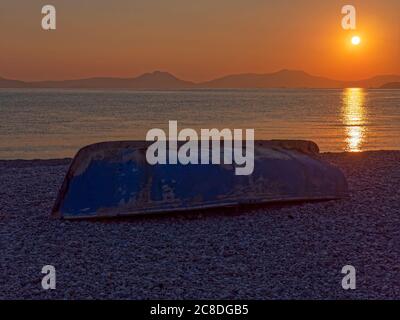 À l'envers. Un vieux bateau sur la plage sous le soleil du matin se levant dans le ciel orange tôt le matin au-dessus de la mer du golfe de Corinthée, Grèce. Je suis sûr que je Banque D'Images