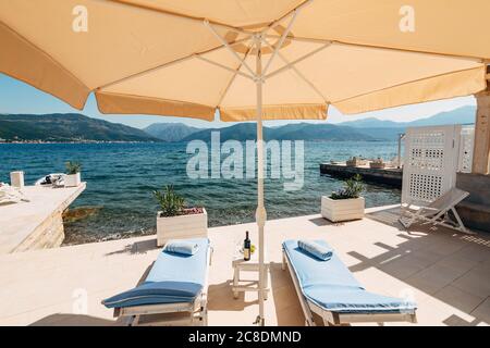 Transats en bois blanc dans la villa, près de la mer. Coussin bleu doux. La cour de la villa avec meubles de plage, coin barbecue, bar et Banque D'Images