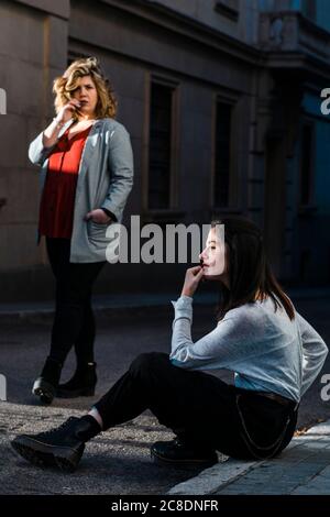 Femme marchant vers une petite amie attentionnés, assise dans la rue en ville Banque D'Images