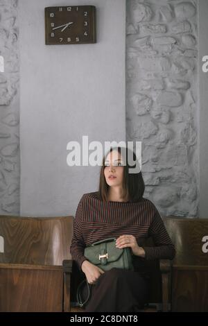 Jeune femme attentionnés avec sac à main assis sur une chaise studio Banque D'Images