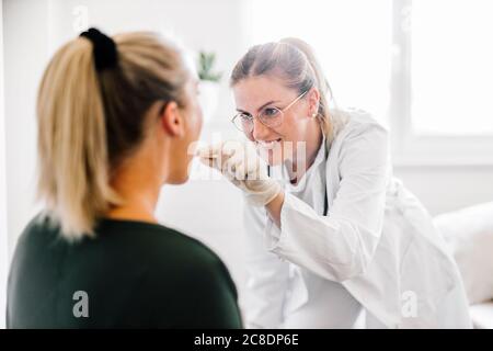 Femme médecin examinant une patiente avec un dépresseur de langue Banque D'Images